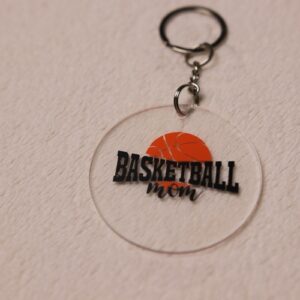 Key chain for the ultimate Basketball Mom. Clear circular disc keychain with fun "Basketball Mom" text featuring an orange basketball graphic.