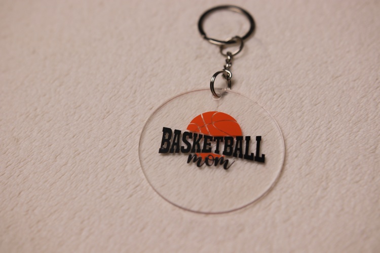 Key chain for the ultimate Basketball Mom. Clear circular disc keychain with fun "Basketball Mom" text featuring an orange basketball graphic.
