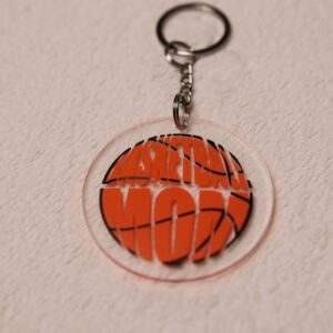 Key chain for the ultimate Basketball Mom. Clear circular disc keychain with fun "Basketball Mom" text in the shape of an orange basketball.
