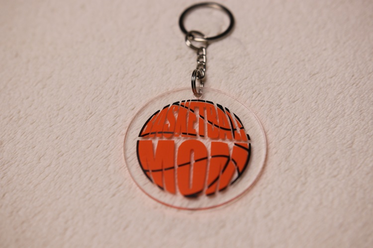 Key chain for the ultimate Basketball Mom. Clear circular disc keychain with fun "Basketball Mom" text in the shape of an orange basketball.