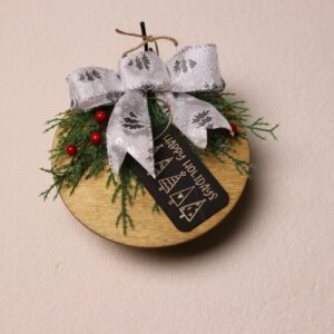 6.5 inch round wooden sign with light oak stain. Cute Christmas gift tag with "Happy holidays" in festive fonts complete with Christmas tree patterns. A splash of colors with pine and holly berries tied together with a white bow showing silver Christmas trees.