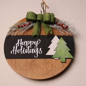 Happy holidays greeting, wooden sign cut in large circle, light oak stain, pine tree cutouts, green ribbon, holly berry and snow frosted pine