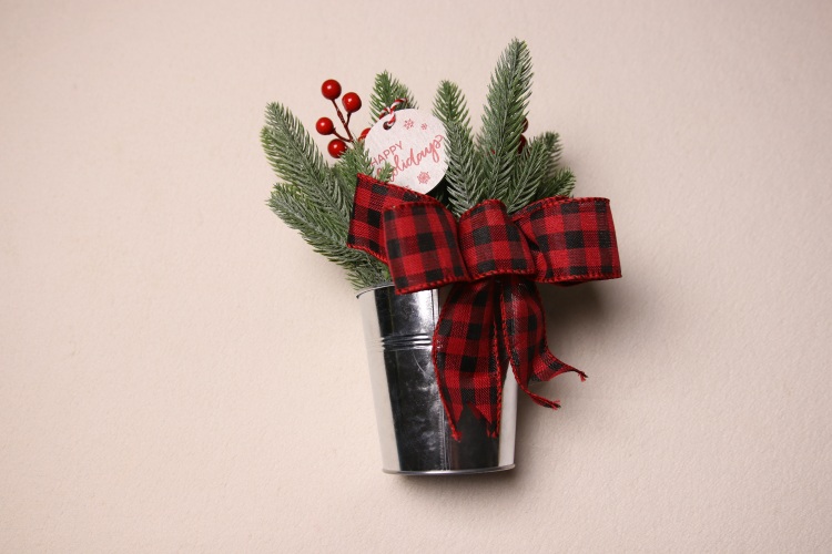 Small table-top holiday decoration. Metal pale full of faux pine needles and holly berries. Complete with cute Christmas gift tag reading "HAPPY Holidays" in fun festive font. Red and black checkered ribbon to complete the Christmas Cheer.