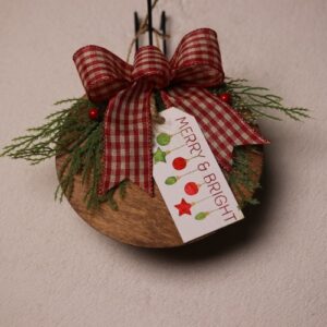 6.5 inch round wooden sign with dark oak stain. Cute and playful gift tag messaging withing your guests a "MERRY & BRIGHT" holiday season. A splash of color with pine and holly berries tied together with a checkered red and white ribbon.