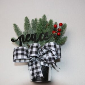 Small table-top holiday decoration. Metal pale full of faux pine needles and holly berries. Complete with cute black and white ribbon below fun, festive wood lettering reading "peace."