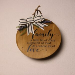 10 inch wooden circular sign with an oak stain and black lettering. Adorned with some pine and lavender tied together with a white and green striped bow.