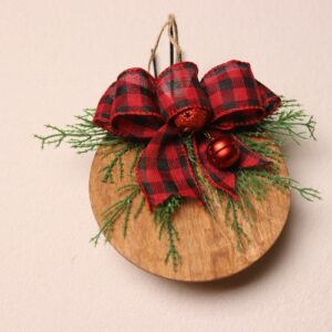 6.5 inch round wooden sign with light oak stain. Cute and playful red metallic jingle bells. A splash of color with pine tied together with a checkered red and black ribbon.