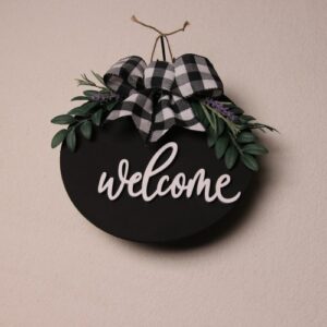 10 inch round sign painted black with cursive white lettering greeting with "welcome." Small green leaves and lavender tied up with a checkered white and black ribbon.
